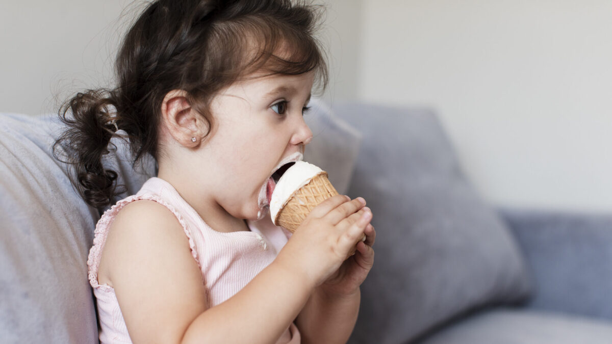 Kisgyerek fagylaltot eszik a kanapén (Fotó: Freepik)